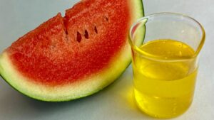 watermelon seed oil in beaker with fresh watermelon