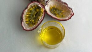 Top down view of fassion fruit seed oil in glass beaker with open passion fruit visible