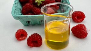 fresh raspberries in teal carton and raspberry seed oil in glass beaker